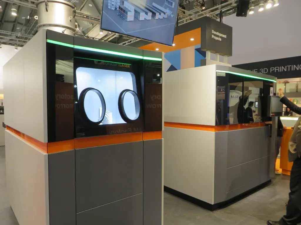 Concept Laser presenteerde in Frankfurt een gedeelte van een modulaire lijn voor AM (of een fabriek voor AM) waarvan het laserstation (rechts op de foto) kan werken met vier lasers. De verschillende modules van de lijn bewegen naar en van het laserprocesstation (foto: Reinold Tomberg)